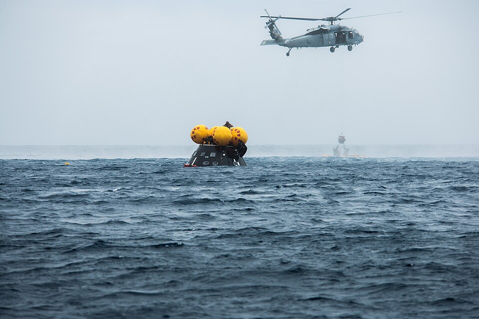 NASA, Navy, and Air Force personnel practice Artemis recovery procedures in the Pacific Ocean as part of Underway Recovery Test-10 off the coast of San Diego. In this photo Naval helicopter pilots from Helicopter Sea Combat Squadron (HSC) 23 “Wildcards” lift a pilot in a basket from an inflatable “f
