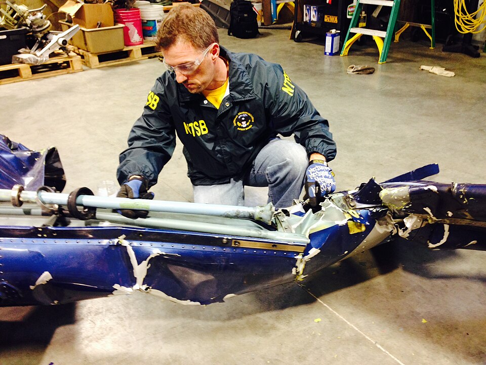 Aviation Safety Investigator Josh Cawthra examines the tail rotor drive shaft of the accident helico