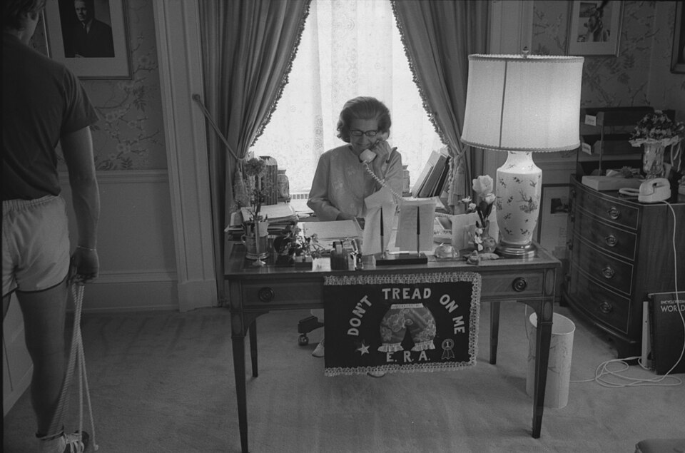 Scope and content:  This photograph depicts First Lady Betty Ford seated at her desk talking on the 