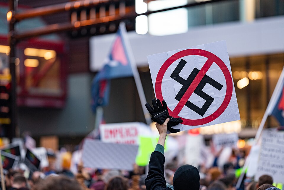 A protester holds a sign with '45' crossed out, which has the visual appearance of a Nazi swastika c